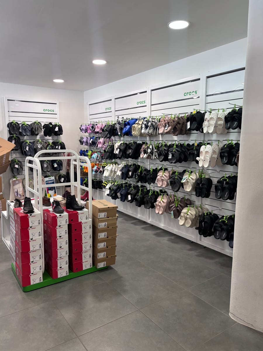 Crocs-Wand mit Sandalen, davor ein Aufsteller mit Schuhkartons