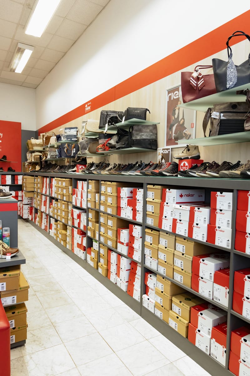 Langes Regal mit Schuhkartons, darüber Schuhe und Taschen