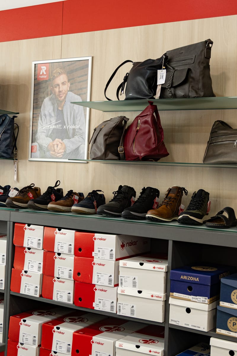 Taschen und Schuhe an der Wand, darunter die Schuhkartons
