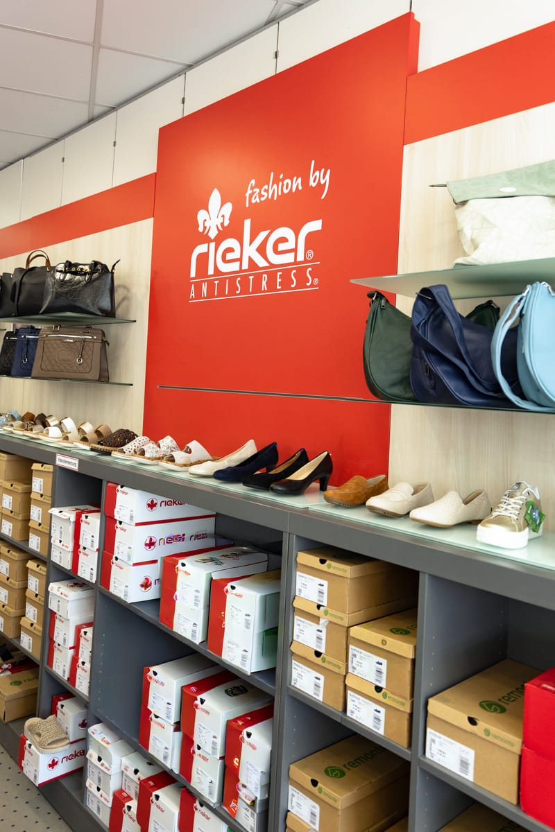 Rote Rieker-Wand mit Taschen, darunter Halbschuhe und Kartons